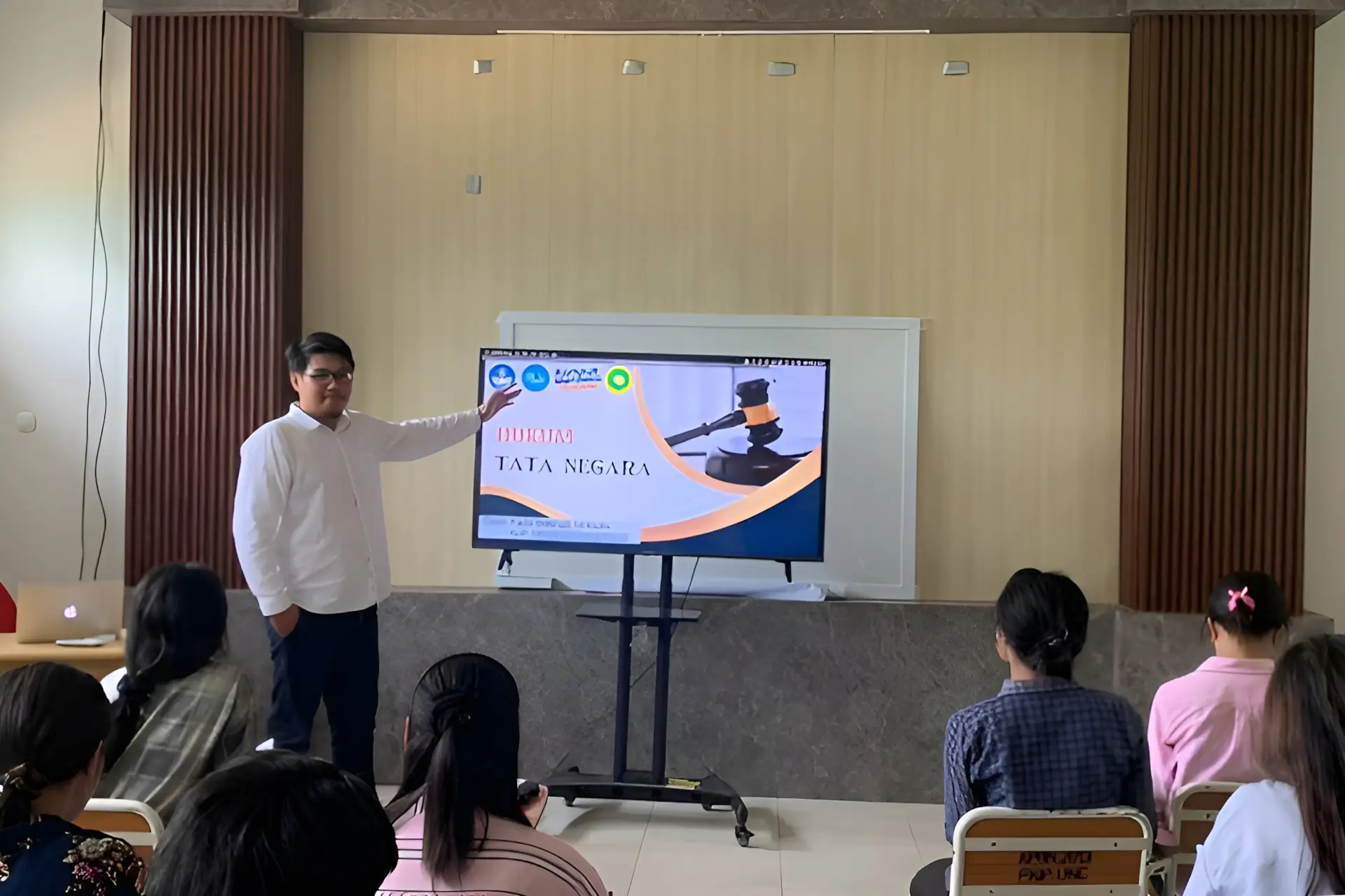 Seorang dosen sedang memberikan materi perkuliahan di dalam kelas